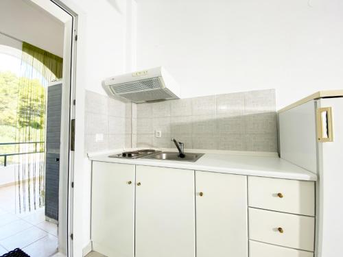 a kitchen with white cabinets and a sink at Posidi Studios in Possidi