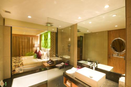 une salle de bain avec un lit, un lavabo et un miroir dans l'établissement Regenta Resort Belagavi, à Belgaum