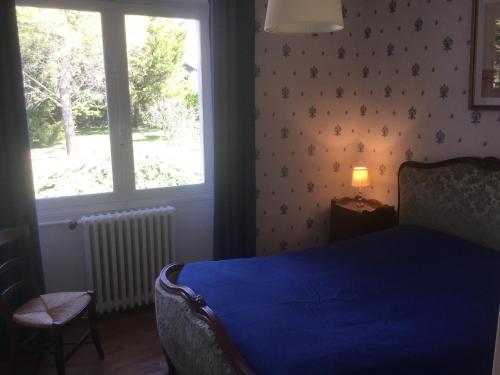 a bedroom with a blue bed and a window at Les Pierrottes in Mornac