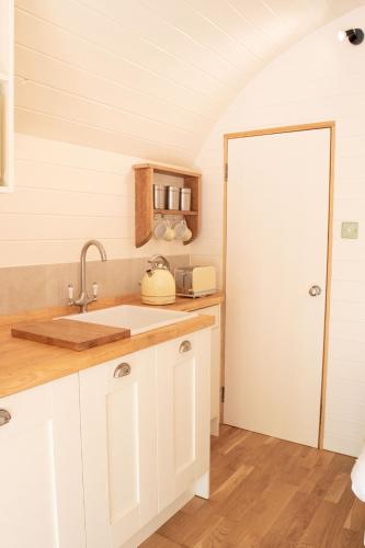 a kitchen with white cabinets and a sink at Orchard Farm Luxury Glamping and Campsite in Glastonbury