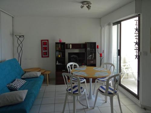 un salon avec un canapé bleu, une table et des chaises dans l'établissement Appartement Cap d'Agde, Vue Mer, 3 pièces, 4/6 personnes, au Cap d'Agde