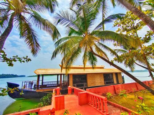 a house on a boat on the water with palm trees at Paradise Lagoon in Kalyānpur