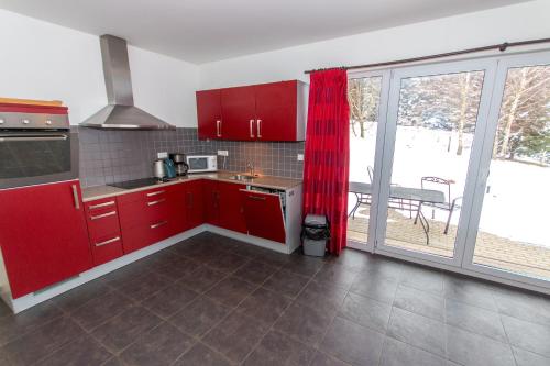 a kitchen with red cabinets and a large window at Villa Slupečná in Lipno nad Vltavou