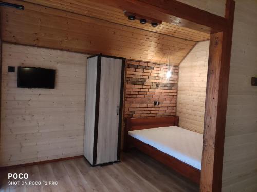 uma pequena cabana com uma cama e uma televisão em Domki letniskowe Kama 514-280-102 em Solina