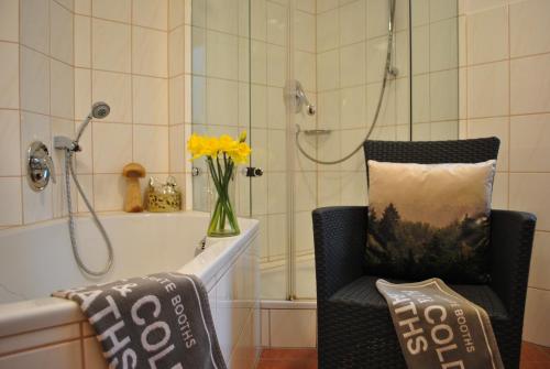 a bathroom with a chair and a shower with a vase of flowers at Goldener Hahn Residence in Baiersbronn