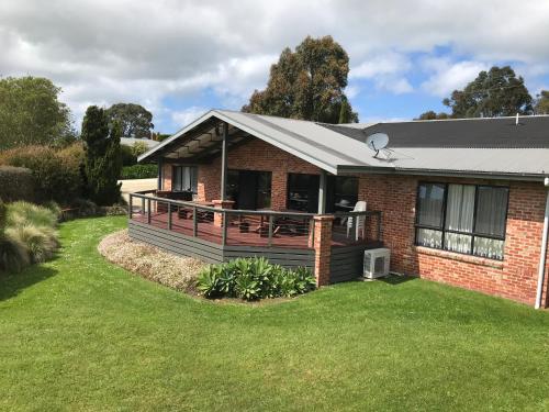 a house with a large deck on a lawn at Prom Coast Holiday Lodge in Waratah Bay