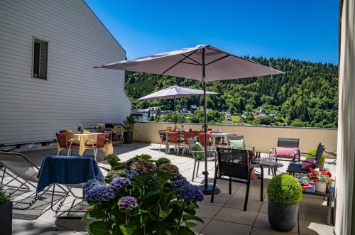 un patio avec tables, chaises et un parasol dans l'établissement Villa les Dahlias, à Le Mont-Dore