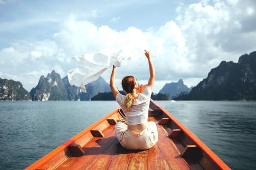 a woman sitting in a boat on the water at 500 Rai Floating Resort in Ratchaprapha