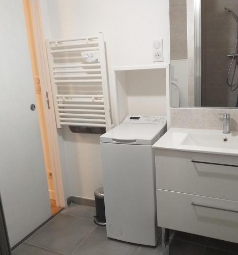 une salle de bain blanche avec un lavabo et un miroir dans l'établissement Les Hortensias, à Caumont-sur-Garonne