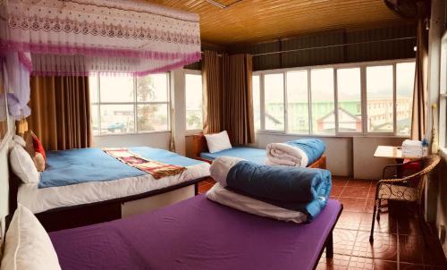two beds and a couch in a room with a window at Meo Vac Cosy Hostel in Mèo Vạc