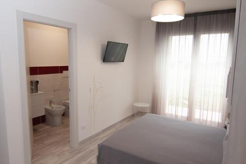 een witte badkamer met een toilet en een raam bij Sogni d'orto in Castiglione della Pescaia