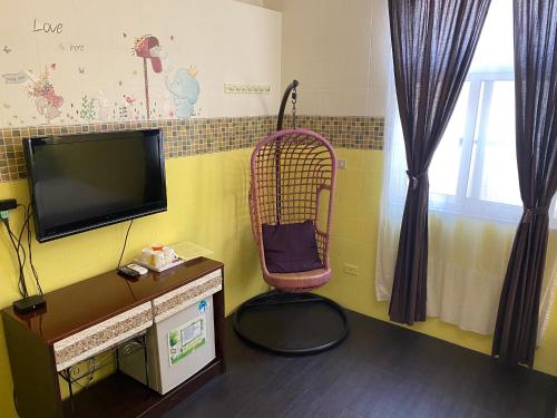 Zimmer mit einem TV und einem Stuhl in einem Zimmer in der Unterkunft 珊瑚礁民宿 in Magong