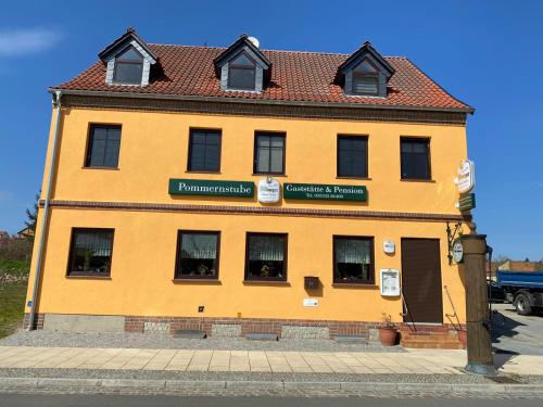 a large yellow building with a red roof at Gaststätte & Pension Pommernstube in Gartz an der Oder