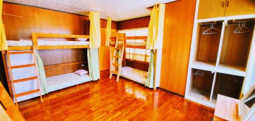 a room with three bunk beds and a wooden floor at Guest House Yun Terrace in Ishigaki Island