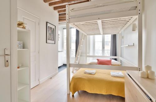 1 dormitorio con 1 cama elevada con manta amarilla en Stylish Mezzanine Studio in the Heart of Paris 3F en París