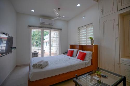 a bedroom with a bed with red pillows and a tv at Adams Cottage Kochi in Cochin