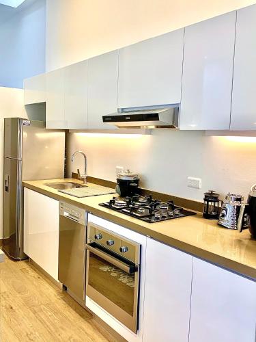 a kitchen with white cabinets and a stove top oven at Casa Rambla Serra Cali in Cali