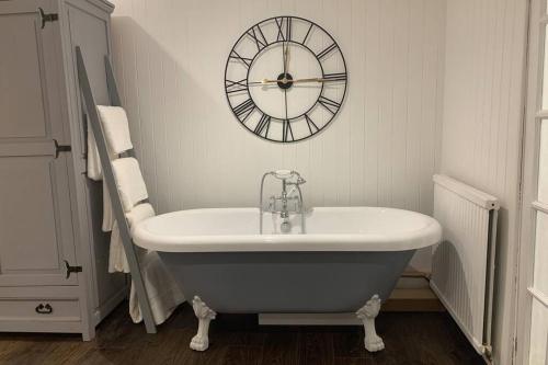 a bathroom with a tub and a clock on the wall at Clock Cottage Self contained Rutland Rural Retreat in Manton