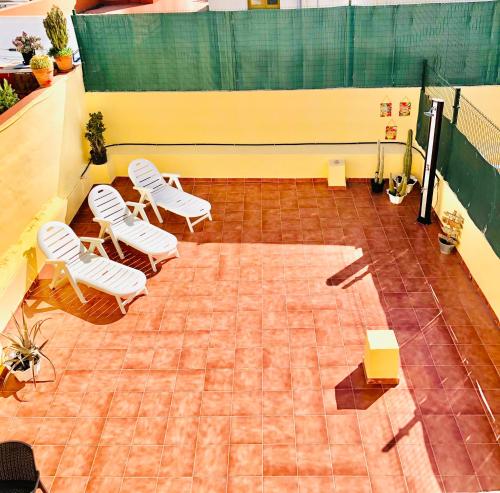 um ginásio com cadeiras brancas e um campo de ténis em Apartamento La real 3 em San Nicolás
