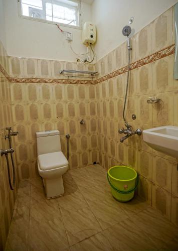 a bathroom with a toilet and a sink and a green bucket at Adams Cottage Kochi in Cochin