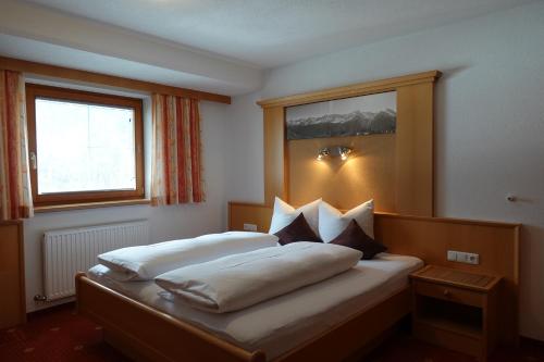 een slaapkamer met een bed met witte lakens en een raam bij Apart La Stella in Kappl