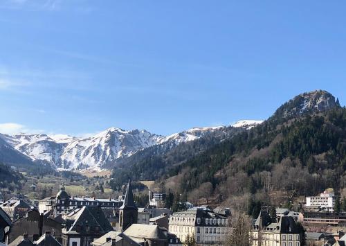 a town with snow covered mountains in the background at Villa les Dahlias in Le Mont-Dore