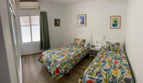 een slaapkamer met twee bedden, een bureau en een raam bij Villa Orquidea with private garden in Playa del Inglés