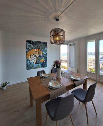 une table à manger avec des chaises et une peinture d'un tigre dans l'établissement Roz de Mer appartement 4 étoiles vue mer, à Perros-Guirec