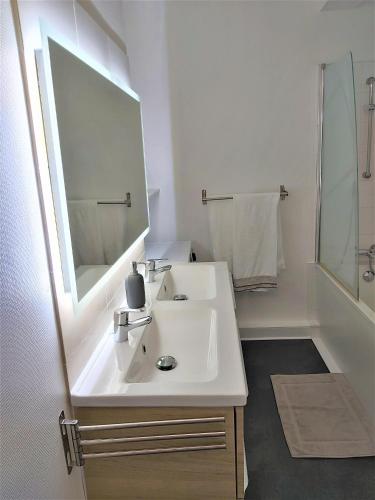 une salle de bain blanche avec un lavabo et un miroir dans l'établissement Roz de Mer appartement 4 étoiles vue mer, à Perros-Guirec