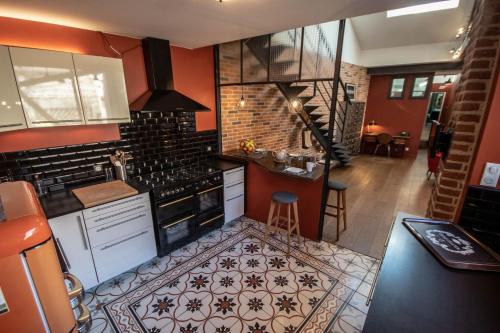 - une cuisine avec des murs rouges et une cuisinière four supérieur dans l'établissement l'Atelier Chambourdin - Maison/Loft Centre Blois, à Blois