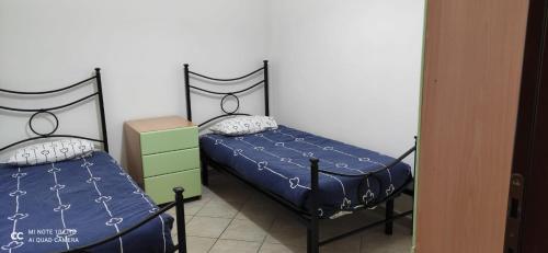 a bedroom with two twin beds with blue sheets and pillows at Trilocale La Corte in Montaquila