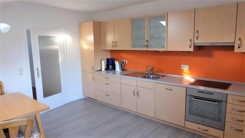 a kitchen with a sink and an orange wall at Ferienwohnung Kaiserblick in Stephanskirchen