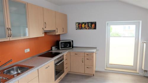 a kitchen with wooden cabinets and a sink and a window at Ferienwohnung Kaiserblick in Stephanskirchen