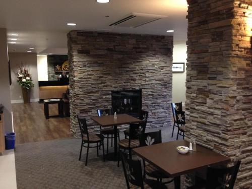 a restaurant with tables and a brick fireplace at Kanata Whitecourt in Whitecourt