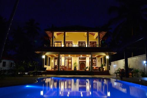 a house with a pool in front of a house at night at Lanka Beach Boutique Bungalows & Grand Villa in Tangalle