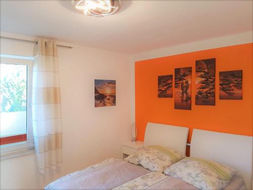 ein Schlafzimmer mit einer orangefarbenen Wand und einem Bett in der Unterkunft Apartment Neptun in Ückeritz