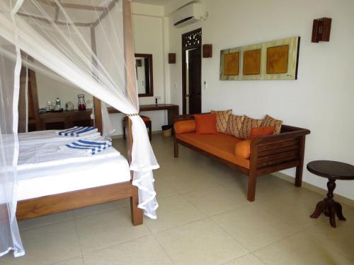 a bedroom with a bed and a couch at Lanka Beach Boutique Bungalows & Grand Villa in Tangalle