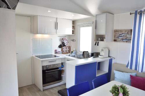 a small kitchen with white cabinets and blue accents at Retiro da Praia da Aguda in Arcozelo