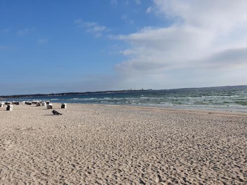 a beach with people sitting on the sand and the ocean at FeWo Machedanz am Hafen Timmendorfer Strand OT Niendorf in Timmendorfer Strand