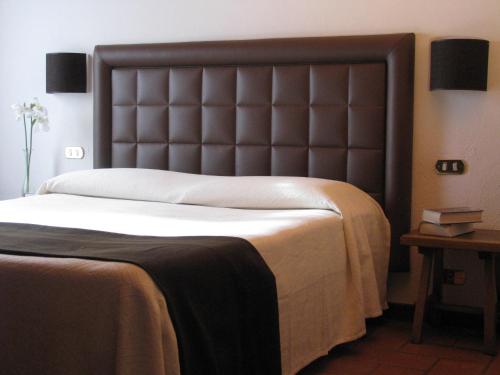 a bedroom with a large bed with a leather headboard at La Locanda Della Chiocciola in Orte