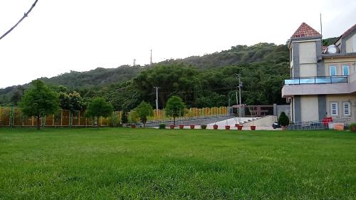 um campo verde com um edifício e uma colina em 隱君子的撒野 