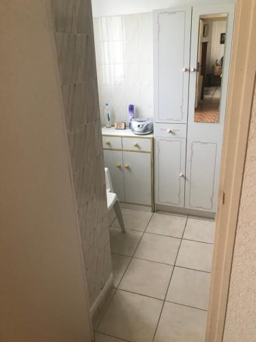 a small kitchen with white cabinets and a tiled floor at Hébergements à La Rive, Accueil ouvert tous les jours jusqu'à 20h00 dernier délai, depuis 30 ans ! Réserver ici svp ! Merci ! Aucun règlement à distance accepté, Paiement par CB, Espèces, Chèque ou Chèques-Vacances impérativement à la remise des clefs ! in Amélie-les-Bains-Palalda