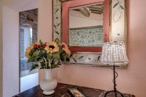a vase with flowers on a table in front of a mirror at Villa Bellaria Lucignano in Lucignano