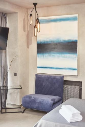 a blue chair in a room with a painting at Stixiya in Odesa