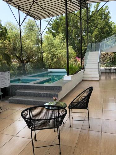 a patio with two chairs and a table and a pool at Rancho Macloy Hotel Spa & Social Events in Yautepec