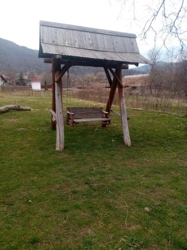 a wooden bench in a field with a roof at Садиба Федорчуків За рікою1 in Sheshory