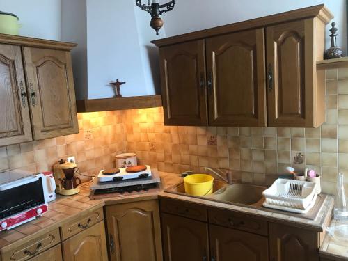a kitchen with wooden cabinets and a counter top at Hébergements à La Rive, Accueil ouvert tous les jours jusqu'à 20h00 dernier délai, depuis 30 ans ! Réserver ici svp ! Merci ! Aucun règlement à distance accepté, Paiement par CB, Espèces, Chèque ou Chèques-Vacances impérativement à la remise des clefs ! in Amélie-les-Bains-Palalda