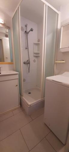 een witte badkamer met een douche en een wastafel bij LES MARINES 2 - Villa en résidence avec piscine à 2 pas de la plage in Saint-Cyprien