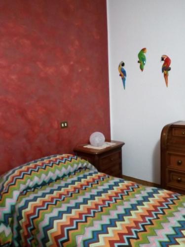 um quarto com uma cama colorida e uma parede vermelha em Alfi BeB em Le Torri