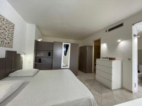 a white bedroom with two beds and a mirror at Hotel L'Orangeraie in Le Lavandou